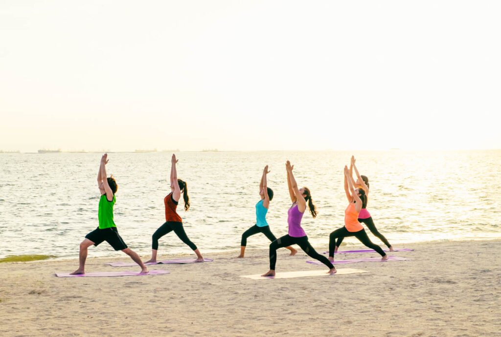 Yoga-Kurs am Meeresstrand bei Sonnenuntergang